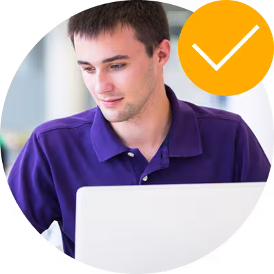 Young man with a slight stubble and purple polo shirt looking at screen